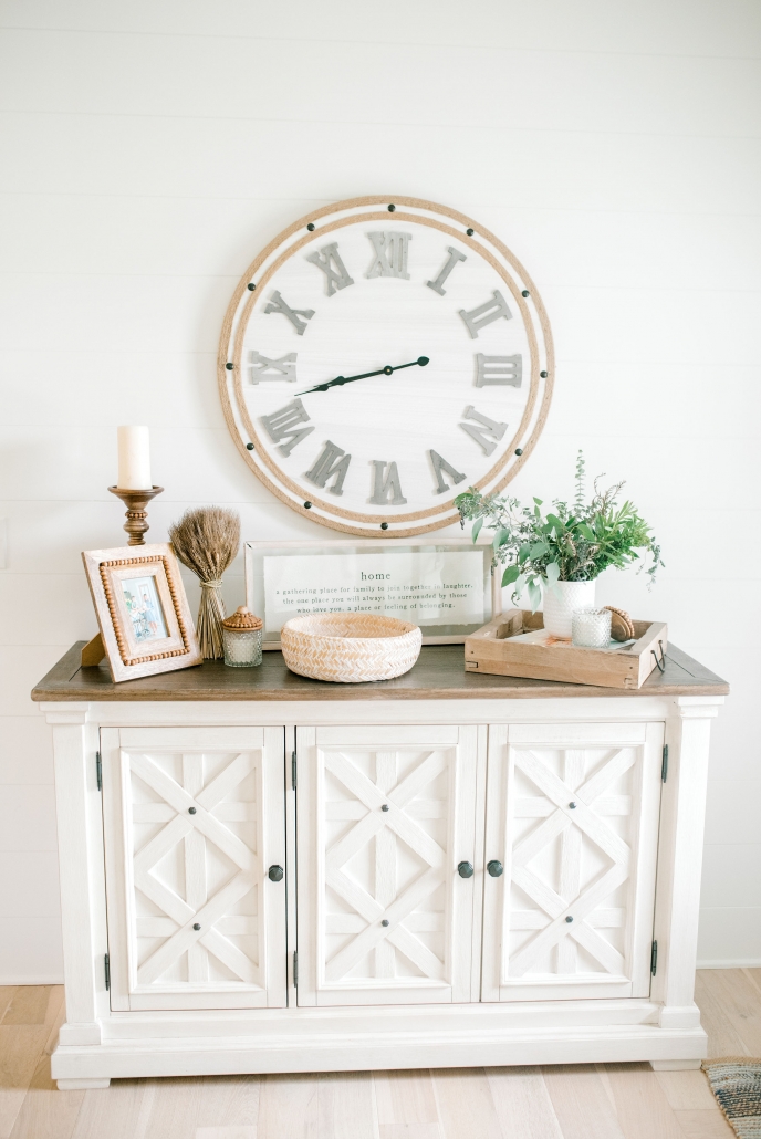 Foyer console table with large clock and other fall decorative items.