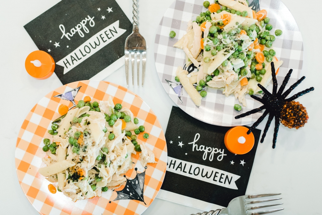 Two plates penne pasta with Halloween napkins.