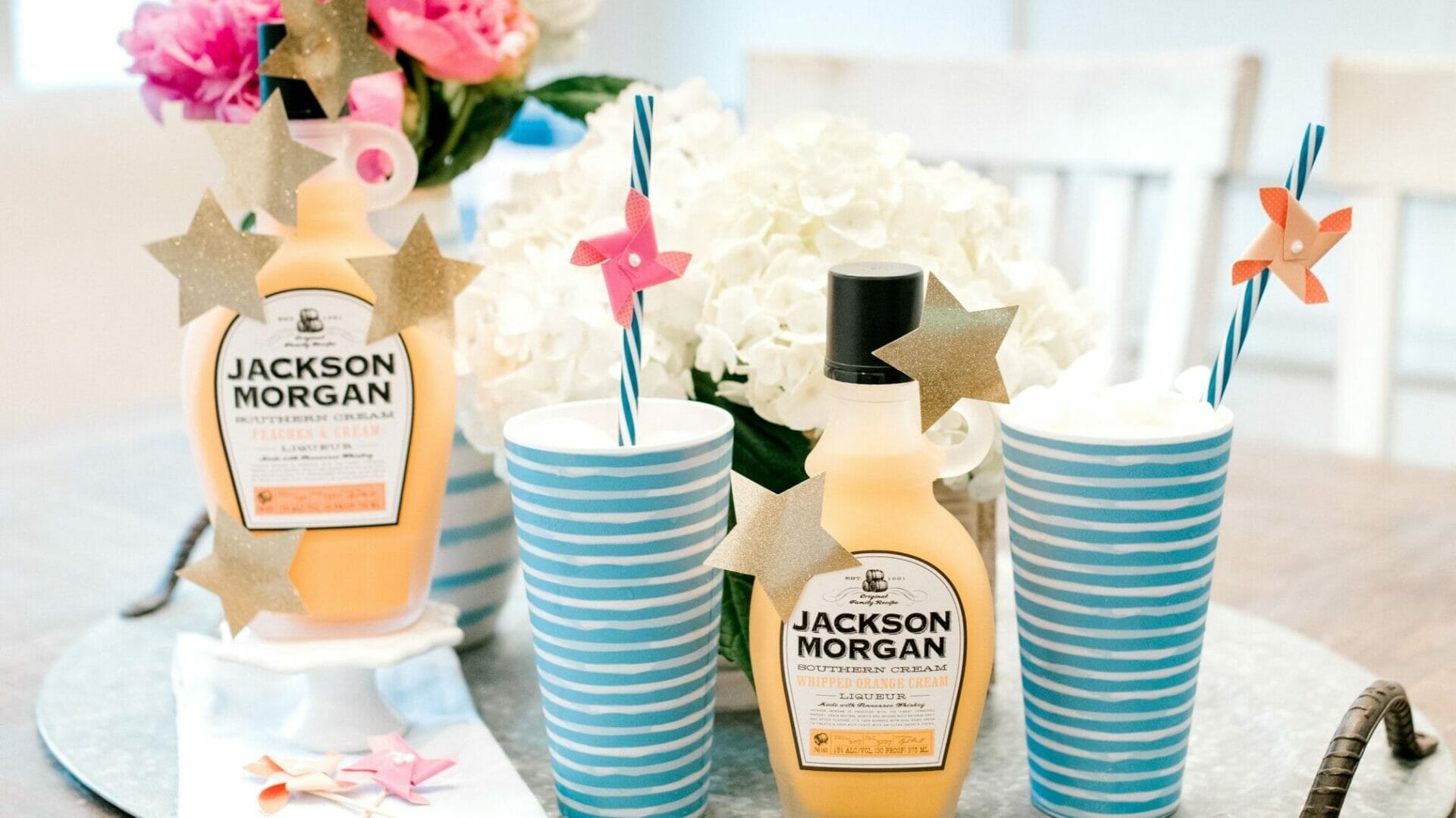 Bottle of Jackson Morgan Southern Cream with striped cups and straws.